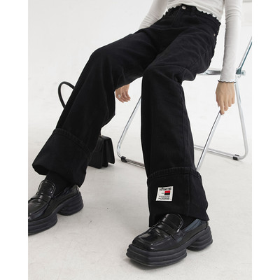 Sirge kõrge vöökohaga naiste teksapükste mudel, mille ühel säärel on embleem