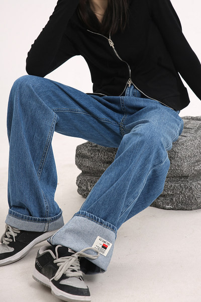 Sirge kõrge vöökohaga naiste teksapükste mudel, mille ühel säärel on embleem