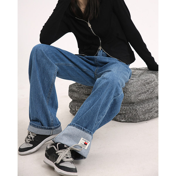 Sirge kõrge vöökohaga naiste teksapükste mudel, mille ühel säärel on embleem