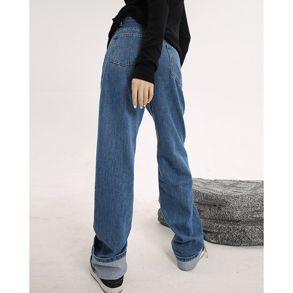 Sirge kõrge vöökohaga naiste teksapükste mudel, mille ühel säärel on embleem