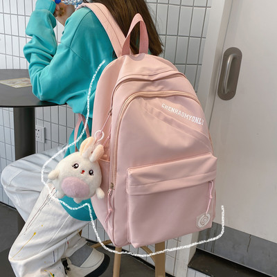 Suur riidest seljakott, millel on kiri ja plüüsist võtmehoidja