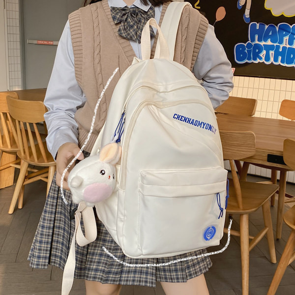 Suur riidest seljakott, millel on kiri ja plüüsist võtmehoidja