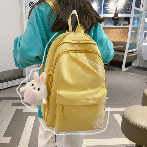 Suur riidest seljakott, millel on kiri ja plüüsist võtmehoidja