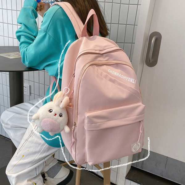 Suur riidest seljakott, millel on kiri ja plüüsist võtmehoidja