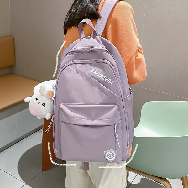 Suur riidest seljakott, millel on kiri ja plüüsist võtmehoidja