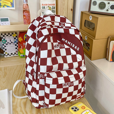 Naiste ruuduline seljakott kirja ja esitaskuga