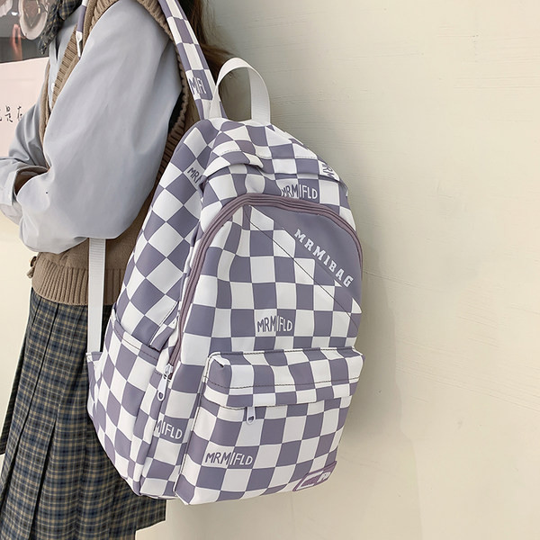 Naiste ruuduline seljakott kirja ja esitaskuga