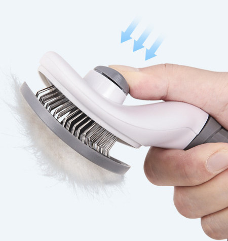 Brush for combing cats with a button to remove hair