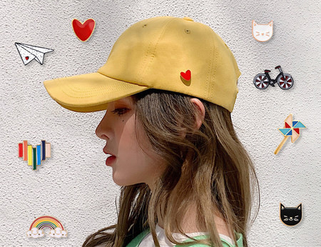 Ženska tekstilna kapa sa šilterom i raznim bedževima