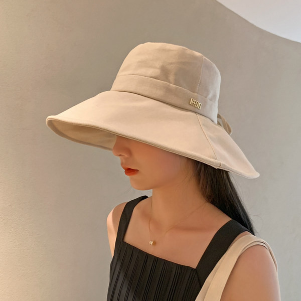 Naiste tekstiilist müts laia ääre ja metallist pealdisega