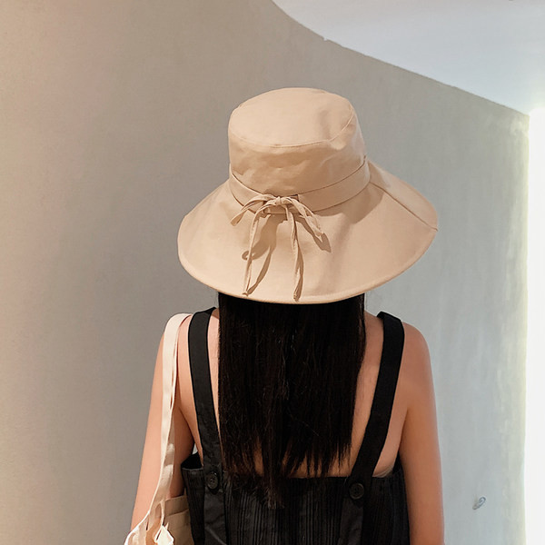 Naiste tekstiilist müts laia ääre ja metallist pealdisega