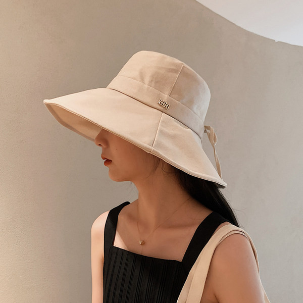 Naiste tekstiilist müts laia ääre ja metallist pealdisega