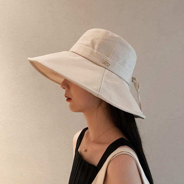 Naiste tekstiilist müts laia ääre ja metallist pealdisega