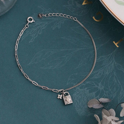 Naiste moodne käevõru, mis on kaunistatud neljalehelise ristiku ja tabalukuga