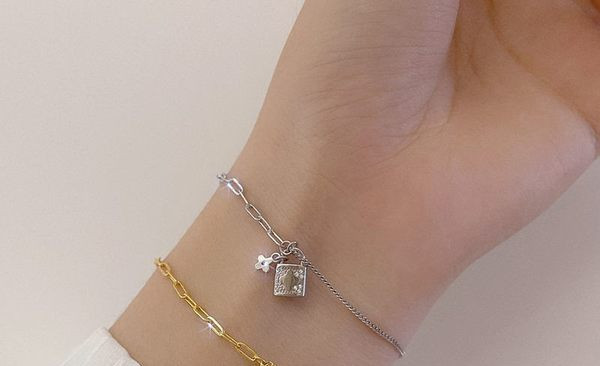 Naiste moodne käevõru, mis on kaunistatud neljalehelise ristiku ja tabalukuga