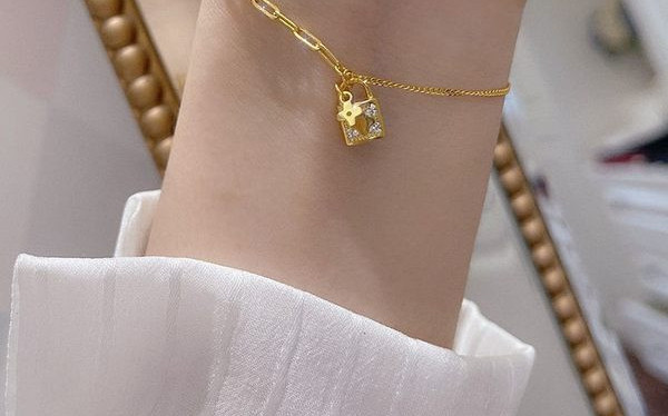 Naiste moodne käevõru, mis on kaunistatud neljalehelise ristiku ja tabalukuga